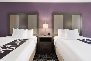 Two plush beds with modern headboards and bedside tables offer a comfortable retreat.