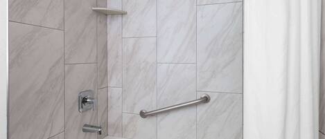 Un baño con bañera, ducha y barra de apoyo.