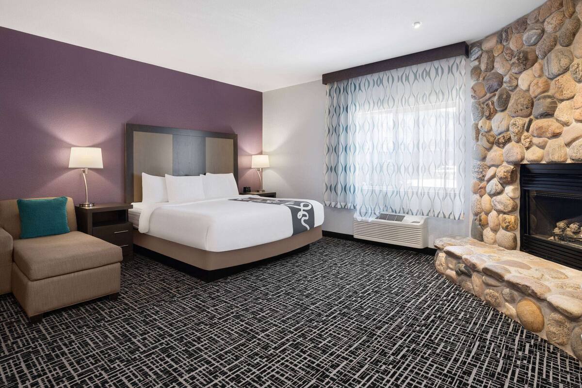 A hotel room with a bed, a sofa, a fireplace, and a stone wall.