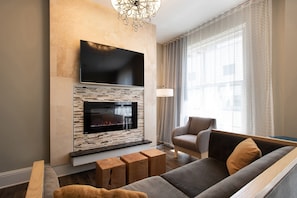 A modern living room with a flat-screen TV mounted above a fireplace, a comfortable sofa, and a wooden coffee table.