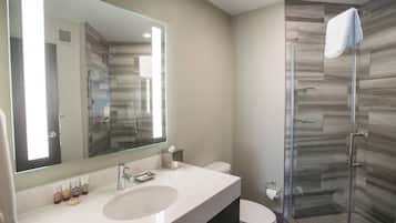 A modern bathroom with a large mirror, a sink, a toilet, and a glass shower enclosure.