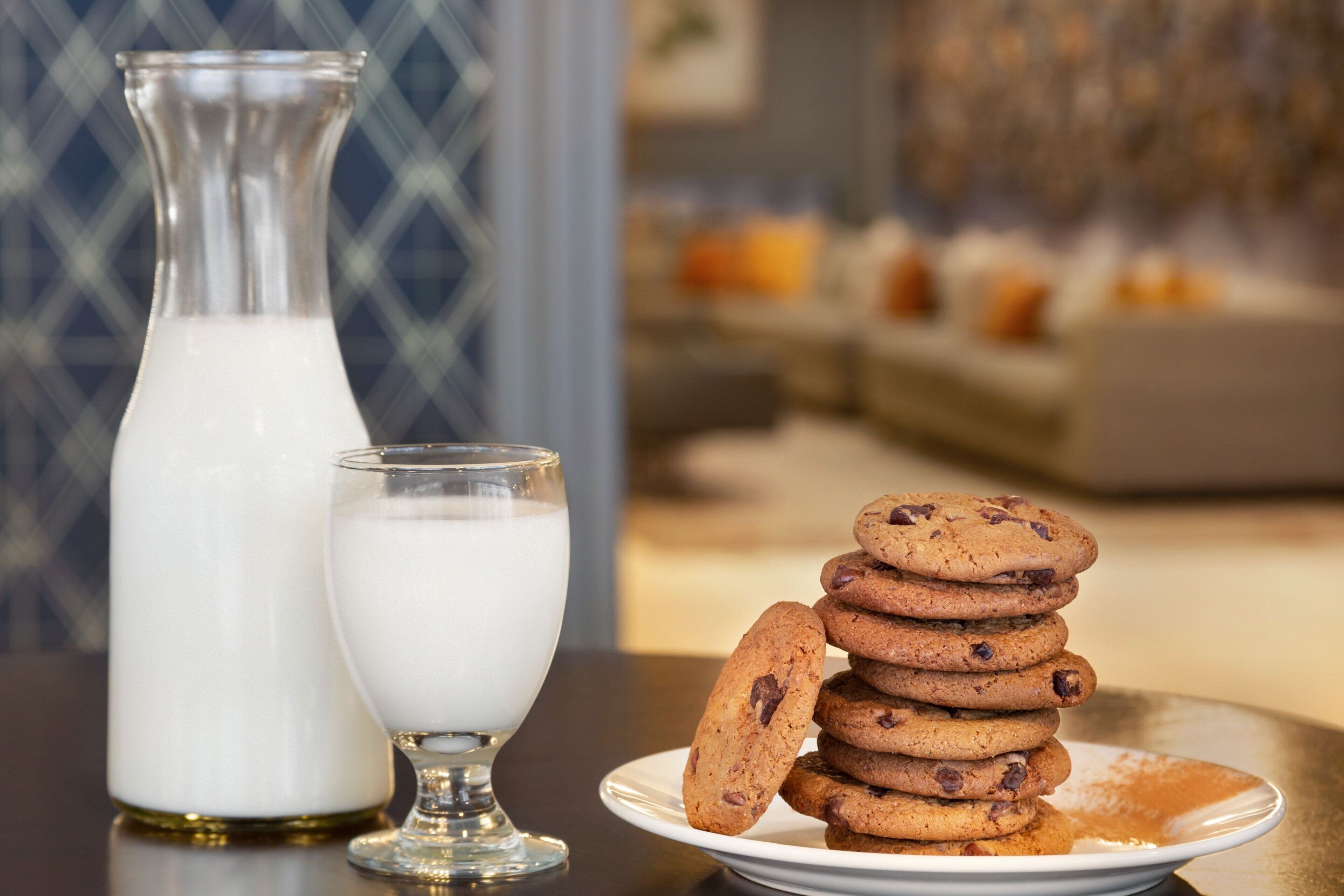 A table with a glass of milk, a milk jug, and a plate of cookies.