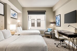 A hotel room with two beds, a desk, a chair, a TV, and a window with blinds. - Magnolia Hotel Denver, A Tribute Portfolio Hotel (Denver)