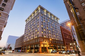 A multi-story hotel with a classic architectural design, featuring a prominent entrance and a large parking area in front. - Magnolia Hotel Denver, A Tribute Portfolio Hotel (Denver)