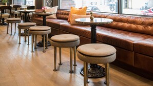 A modern interior with a leather sofa, round tables, and large windows offering a view of the street. - Magnolia Hotel Denver, A Tribute Portfolio Hotel (Denver)