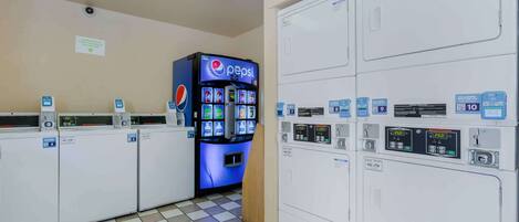 A laundry facility with multiple washing machines and a Pepsi vending machine.