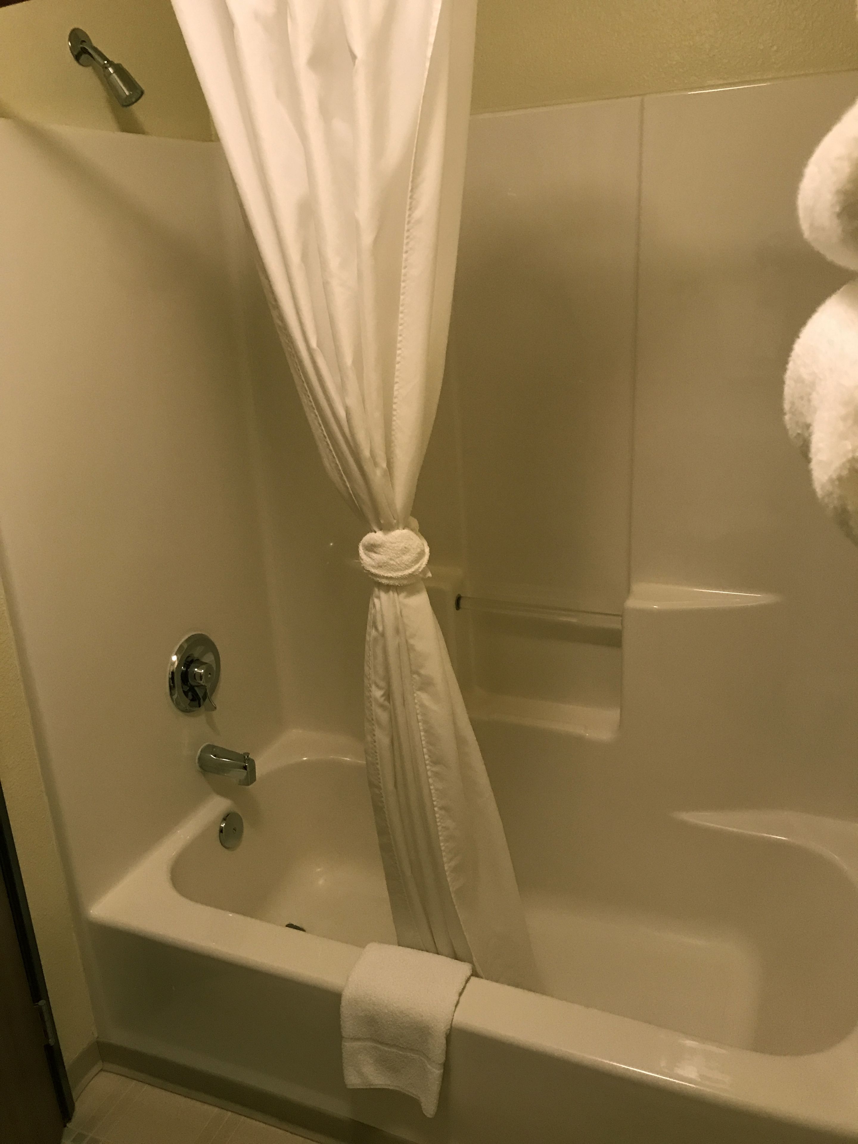 A bathroom with a bathtub, a shower curtain, and a towel rack.