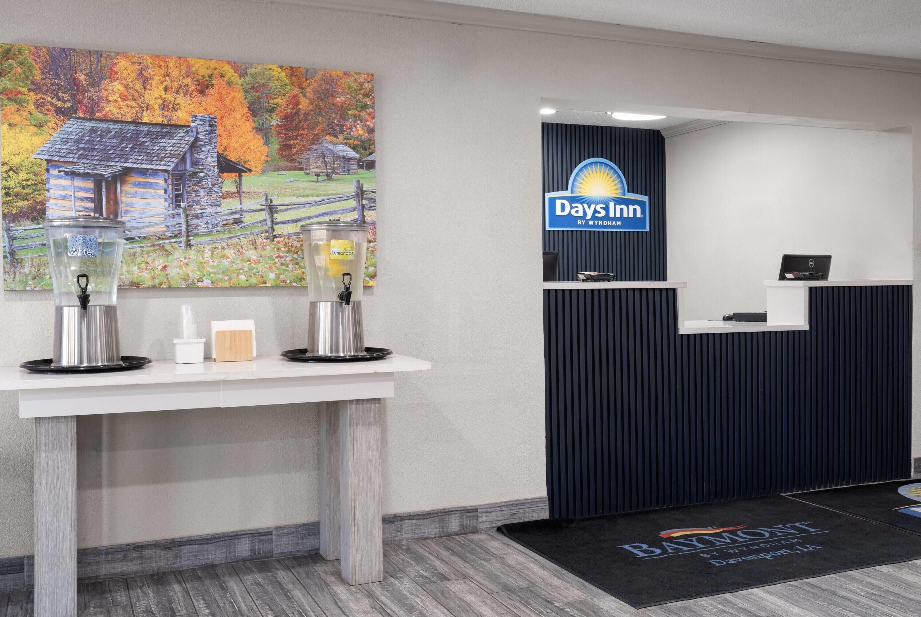 A reception area with a Days Inn sign, a coffee station, and a laptop on a desk.