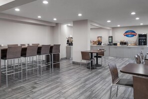 A breakfast area with a counter, seating, and kitchen appliances. - Baymont by Wyndham Davenport (Davenport)