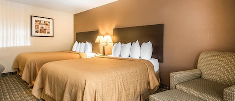 A hotel room with two beds, a sofa, a lamp, and a framed picture on the wall.