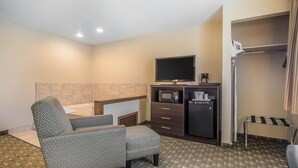 A hotel room with a bed, a TV, a mini-fridge, a microwave, a small table, and a chair. - Quality Inn & Suites Decorah (Decorah)
