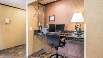 A reception area with a desk, computer, chair, phone, and decorative plants.
