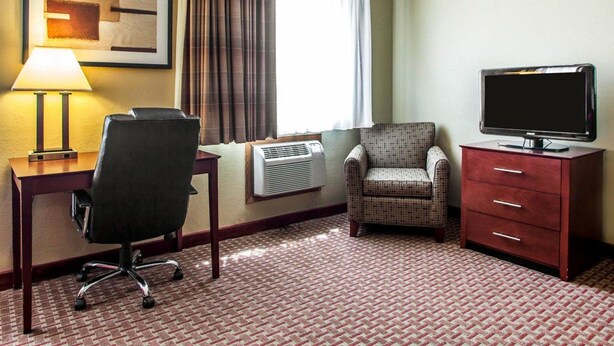 Une chambre d’hôtel équipée d’un bureau, d’une chaise, d’une télévision et d’une commode rouge.
