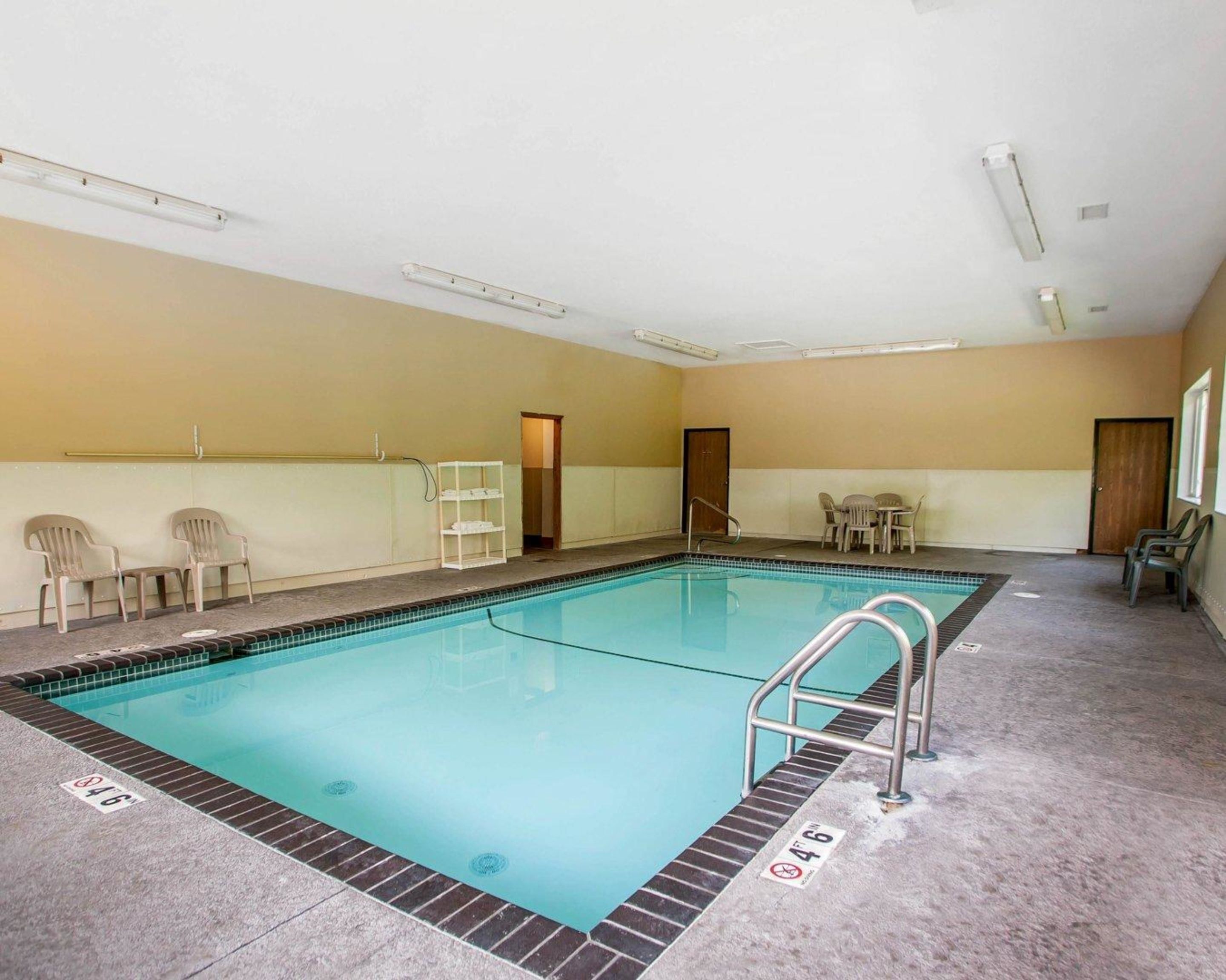 An indoor swimming pool with a clear water surface, a pool ladder, and a tiled floor.