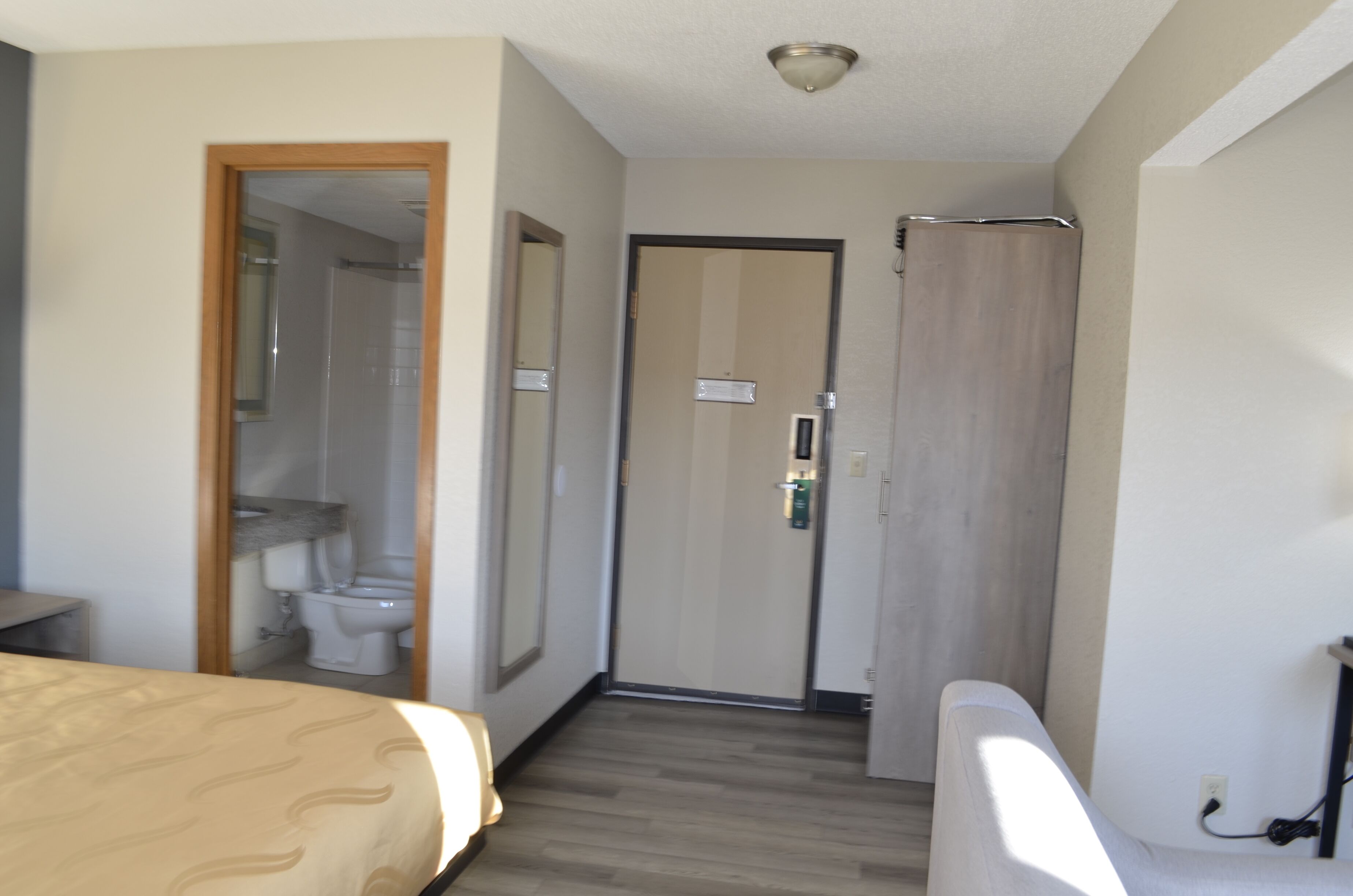 Une chambre d’hôtel comprenant un lit, une salle de bain avec des toilettes et un miroir, ainsi qu’un espace douche.