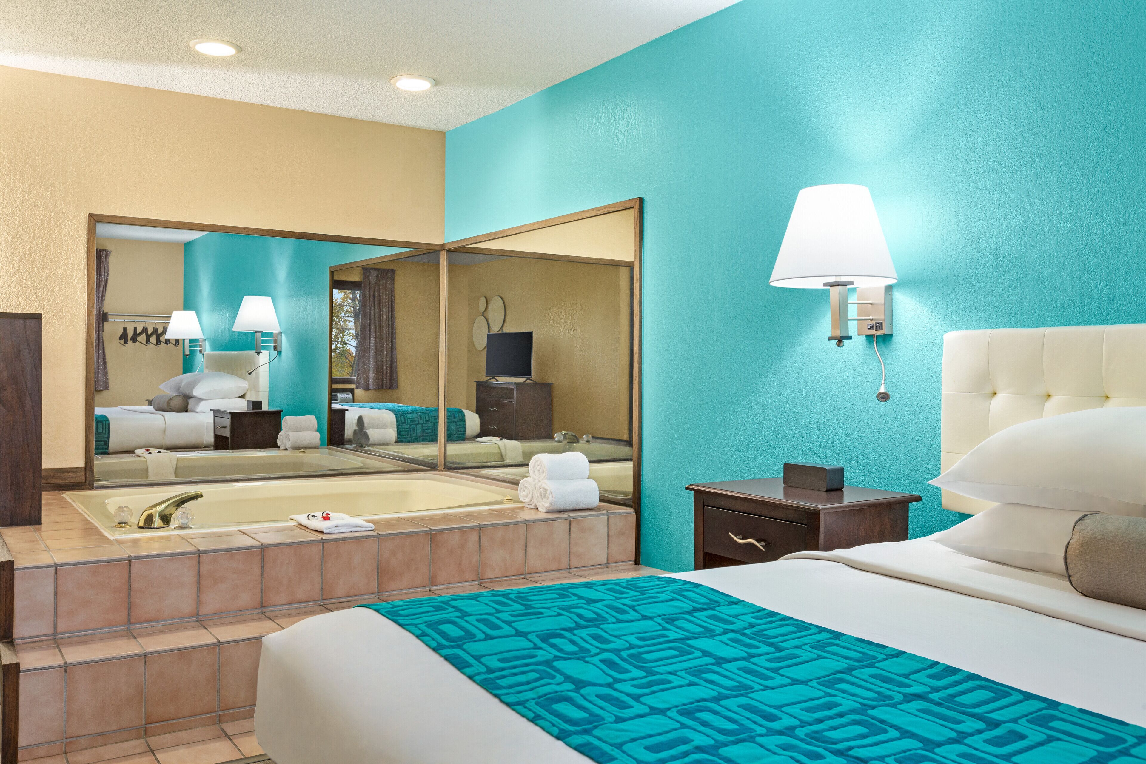 Une chambre d’hôtel avec un grand lit, une salle de bain avec une baignoire et un miroir.