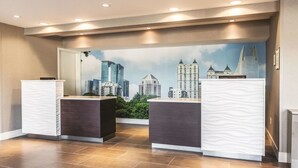 A reception area with two counters, a cityscape mural, and a tiled floor. - La Quinta Inn & Suites by Wyndham Atlanta Midtown - Buckhead (Atlanta)