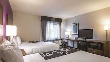 Habitación de hotel con dos camas, un escritorio con computadora, televisión y microondas.