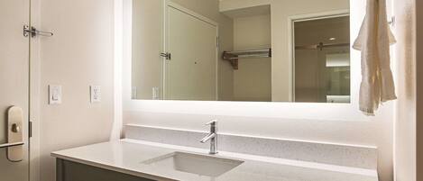 Une salle de bain avec un grand miroir, un lavabo et un porte-serviettes.