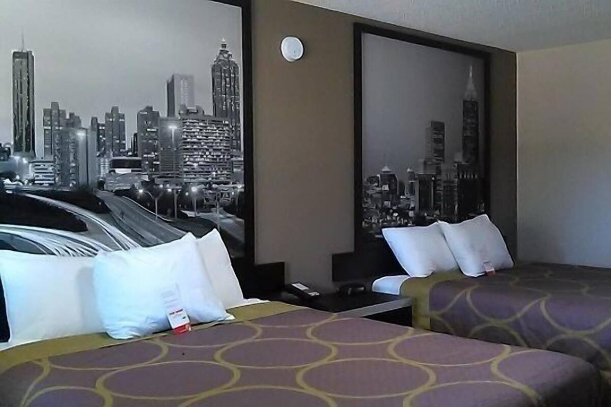 A hotel room with two beds, a cityscape view, a round clock, and a nightstand.