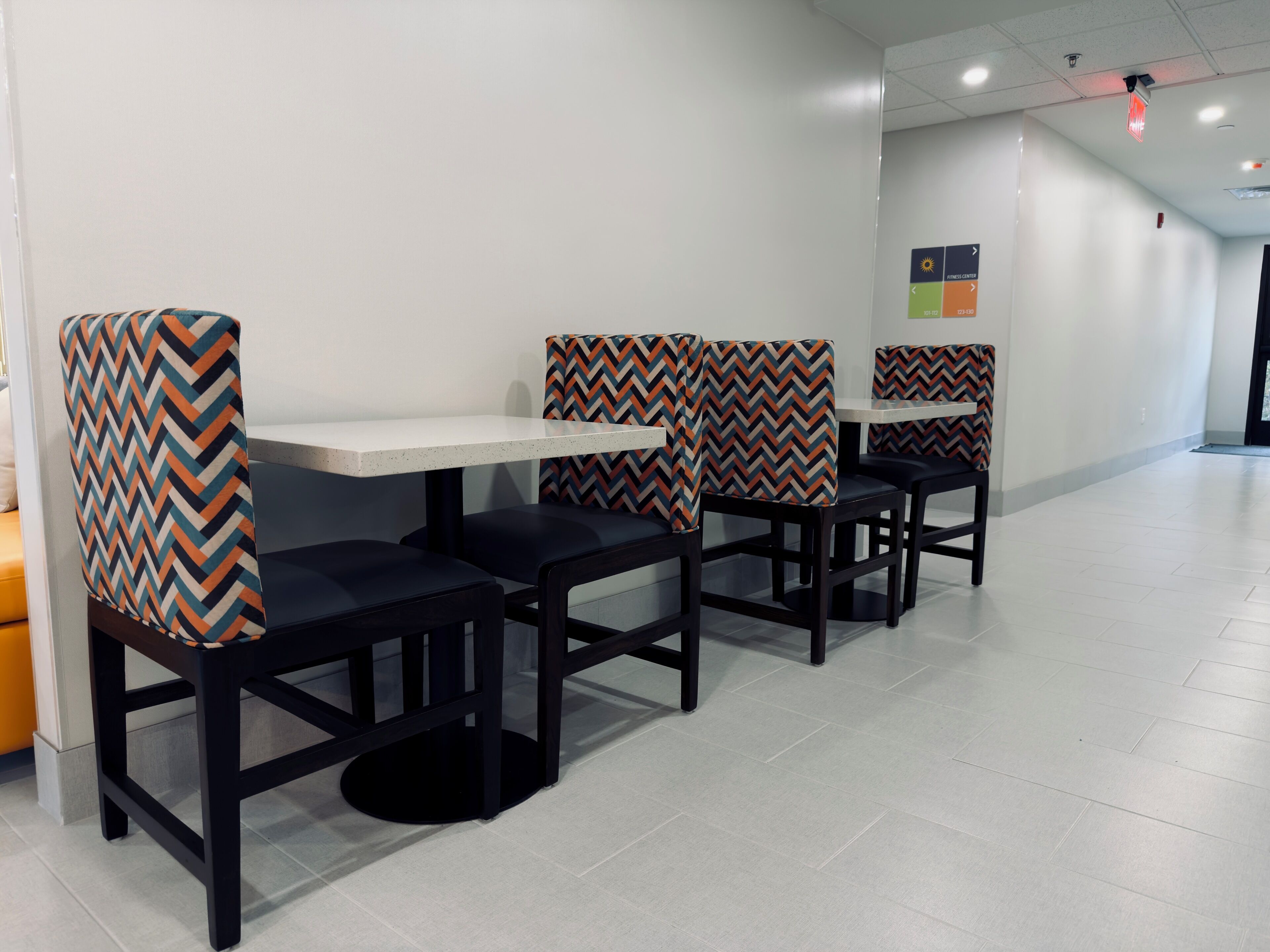 A modern restaurant with black chairs and white tables, featuring a chevron-patterned cushion.