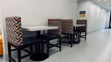A modern restaurant with black chairs and white tables, featuring a chevron-patterned cushion.