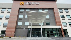 A modern hotel with a prominent 'La Quinta' sign, featuring a sun logo. It has a symmetrical facade with large windows and a covered entrance area. - La Quinta Inn & Suites by Wyndham Atlanta Roswell (Roswell)