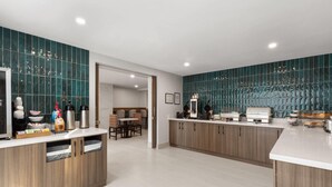 A modern kitchen with wooden cabinets, a marble countertop, and a backsplash with a reflective pattern. - La Quinta Inn & Suites by Wyndham Atlanta Roswell (Roswell)