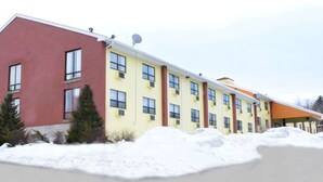 A multi-story building with a red and yellow facade, multiple windows, and a snow-covered ground.