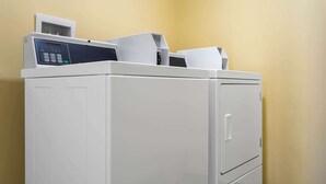 A white laundry machine with a control panel, located in a room with yellow walls.
