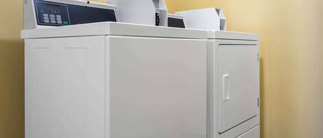 A white laundry machine with a control panel, located in a room with yellow walls.