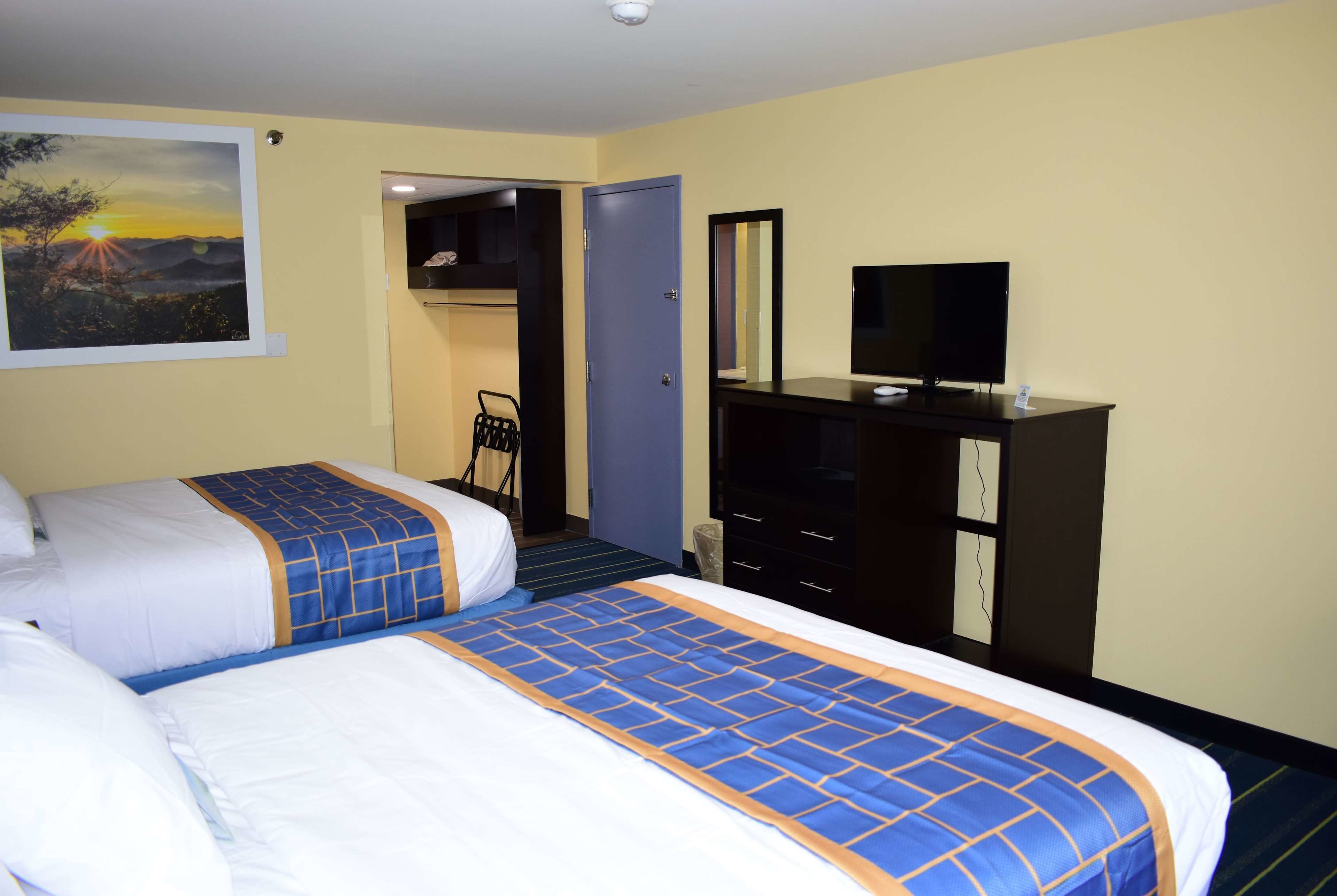 Quarto de hotel com duas camas, uma mesa de trabalho e um guarda-roupa.