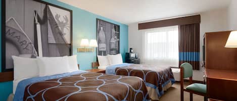 A hotel room with two beds, a desk, a chair, a TV, and artwork on the walls.