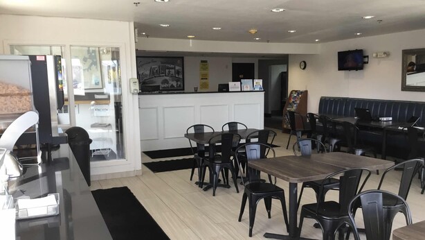 A restaurant with a counter, tables, and chairs. - Super 8 by Wyndham Portland ME (Westbrook)
