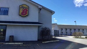 A Super 8 hotel with a large sign, a parking lot, and a clear blue sky. - Super 8 by Wyndham Portland ME (Westbrook)