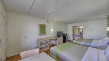 A hotel room with two beds, a desk, a television, and a mirror.