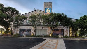 A building with a stone facade, a prominent '6' sign, and a parking lot with marked handicapped spaces.