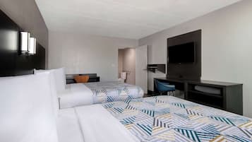 Une chambre d’hôtel avec deux lits, un bureau, une chaise, un téléviseur à écran plat et une grande fenêtre.