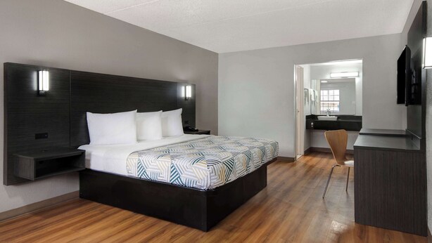 A modern bedroom with a large bed, bedside tables, a desk, and a chair.