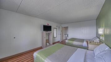 Habitación de hotel con dos camas, televisión, armario y espejo.