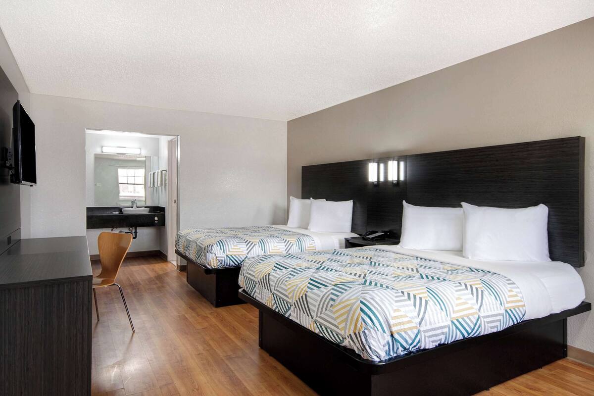 Une chambre d’hôtel moderne avec deux lits, un bureau et un miroir.