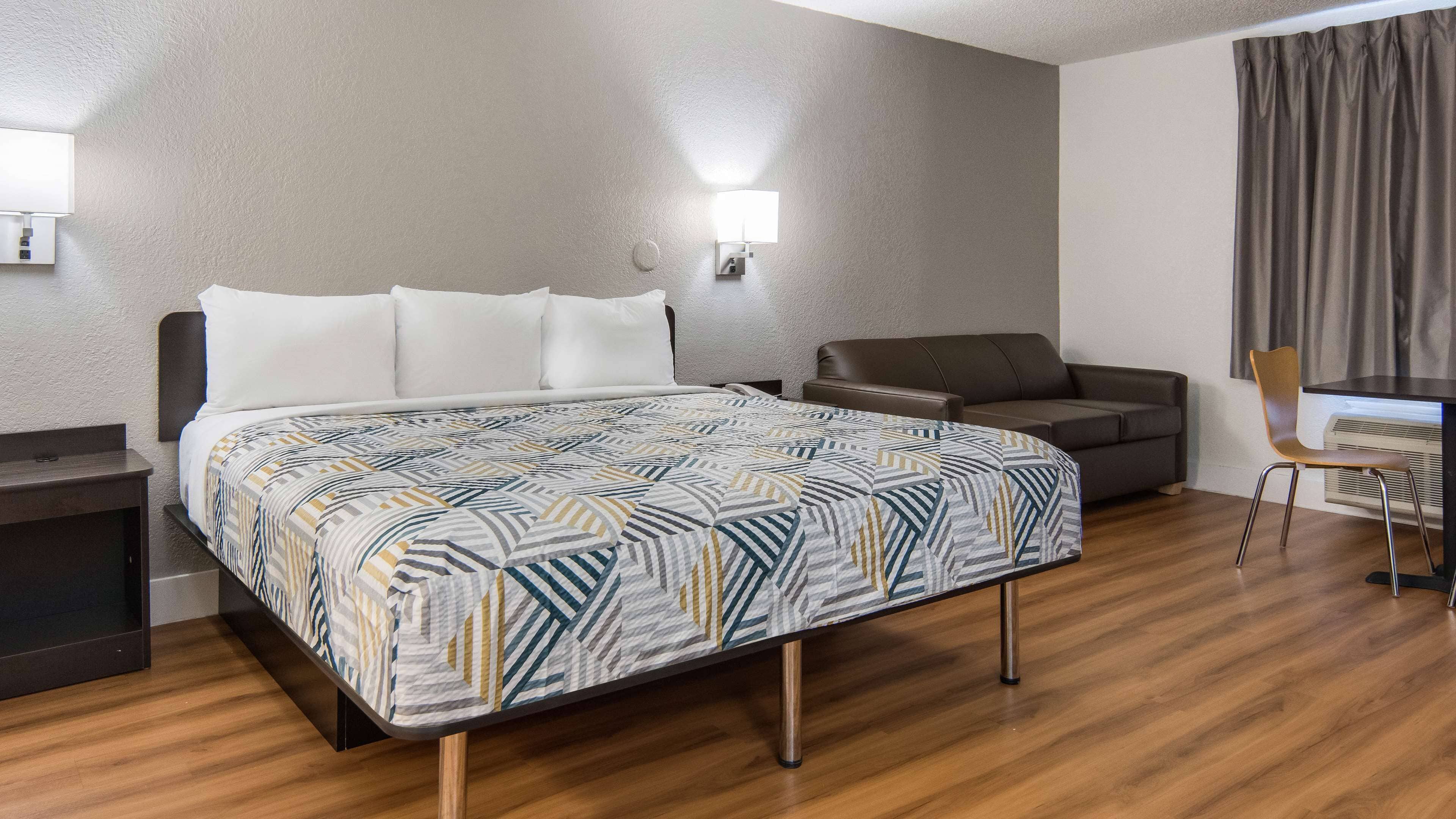 A hotel room with a bed, a sofa, a desk, and a chair.