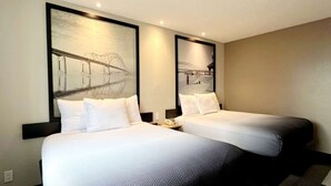 A hotel room with two beds, a nightstand, and a wall-mounted mirror.