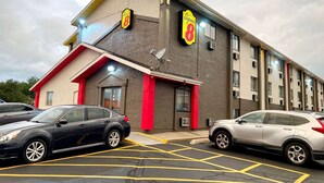 A building with a sign reading "Super 8" and a satellite dish. There are two cars parked in front.
