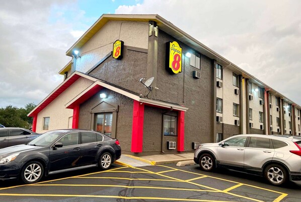 Un edificio con un letrero que dice "Super 8" y una antena parabólica. Hay dos coches estacionados enfrente.