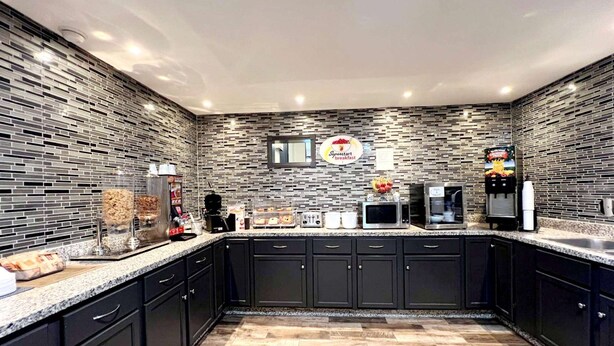 A modern kitchen with black cabinets, a granite countertop, and a patterned backsplash.