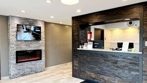 A modern reception area with a stone wall, a flat-screen TV, a fireplace, and a reception desk.