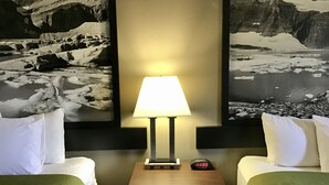 A hotel room with two beds, a nightstand with a lamp, a clock, and two large black-and-white landscape paintings on the wall. - Super 8 by Wyndham Helena (Helena)