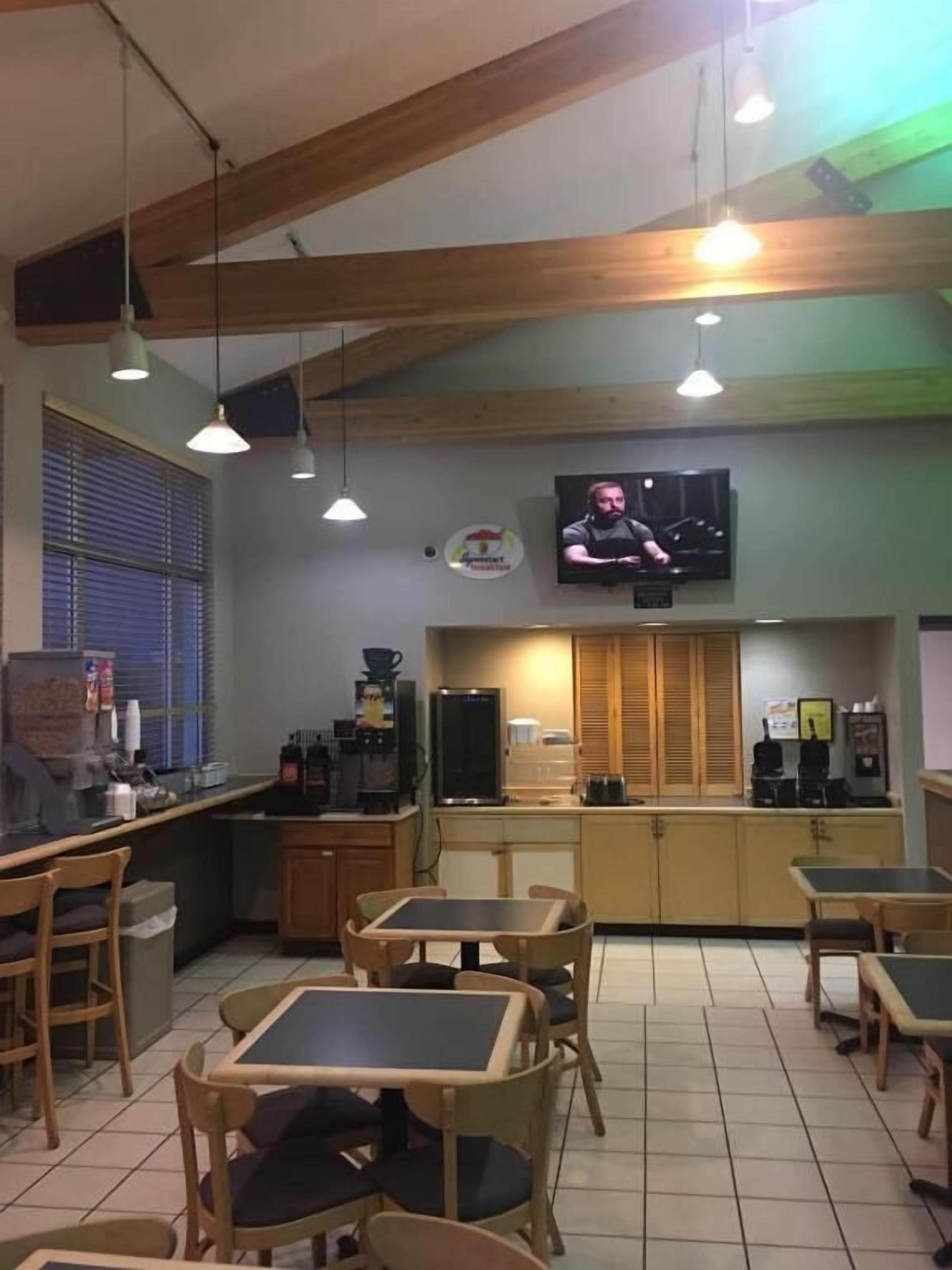 Un café con muebles de madera, un televisor en la pared y una máquina de café.
