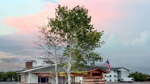 A building with a rustic exterior, a flag, and a parking lot. - Super 8 by Wyndham Helena (Helena)